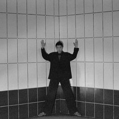 a man standing in front of a tiled wall with his hands up and arms raised