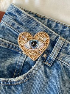 a heart shaped brooch sitting in the back pocket of a pair of jeans