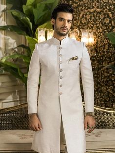 Item Contains:  Sherwani Kruta  Pyjama Fabrics :   Premium luxury jacquard/brocade  Colours :  Cream Style and Designs : Sherwani has mandarin collar and long sleeves with a full button placket asymmetric hem and multiple slits  Kurta has mandarin collar and long sleeves with a full button placket symmetric hem and multiple slits  White coloured churidar has a drawstring closure with nara Size :  Slim fit  Model height is 6 fitt and wearing 40 size  Material and Care :  Raw Silk  Brocade silk  S Luxury White Mandarin Collar Bandhgala, Groom's Cream Kurta With Naqshi, Cream Kurta With Naqshi For Groom's Wedding, Cream Kurta With Naqshi For Groom, Cream Kurta For Groom At Eid, Cream Kurta For Groom On Eid, Cream Kurta For Groom Eid Celebration, Cream Naqshi Kurta For Groom, Cream Naqshi Sherwani For Groom