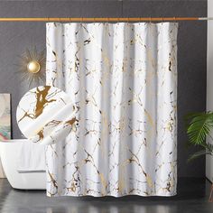 a white shower curtain with gold paint splattered on it, next to a potted plant