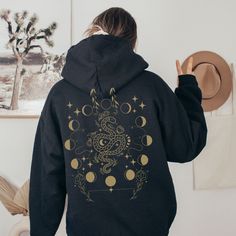 Celestial Moon Phase Hoodie with Back Print Design! Perfect for those who are fans of dark academia, Y2K fashion, and all things celestial. This hoodie features a stunning moon phase design on the back, adding a touch of mystique and style to your outfit. The snake and star accents further enhance the celestial aesthetic, making this hoodie a standout piece. Made from high-quality materials, this hoodie is not only stylish but also comfortable. Embrace your love for all things celestial with our Celestial Moon Phase Hoodie! 🖤 For oversized order 1-3 sizes up, refer to listing photos for sizes. RUNS ON THE SMALLER SIDE 🖤 Gildan 18500 🖤 Some Shrinkage may occur with washing 🖤 This unisex heavy blend hooded sweatshirt is relaxation itself.  🖤 Made with a thick blend of cotton and polyest Aesthetic Winter Hoodie, Winter Aesthetic Hooded Hoodie, Y2k Hoodie, Snake Print, Y2k Fashion, Outfits Aesthetic, Put On, Cold Day, Hoodie Print