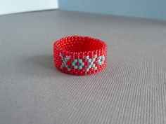 "XoXo, hugs and kisses design ring. Custom,seven row Delica, (tiny even size glass seed bead,) flexible ring with your choice of color, hand woven ring .  Ring is hand woven together off-loom using the peyote stitch . Bead colors are Electric Cherry and with matte Turquoise \"O\" and Aqua Rainbow \"X\". (Custom color combinations are available by request. Select 'Custom' option from the drop down menu and write your desired colors in the 'Note to Seller' box at checkout.) I make each ring to ord Woven Ring, Beaded Ring, Hugs And Kisses, Beaded Rings, Ring Ring, Seed Bead, Embroidered Friendship Bracelet, Ring Designs, Hand Woven