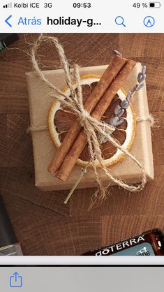 a box with cinnamon sticks tied to it on top of a wooden table next to an orange slice