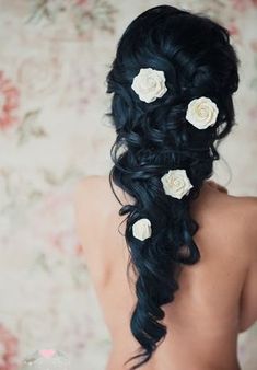 the back of a woman's head with long hair and flowers in her hair