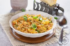 a white bowl filled with pasta sitting on top of a table next to silverware