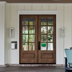 the front door to a house with two glass doors and a blue chair in front