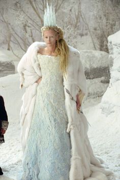 a woman in a blue dress and white fur coat