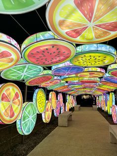 an array of brightly colored umbrellas hanging from the ceiling above a walkway at night