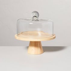 a wooden stand with a glass dome on top and a white wall in the background