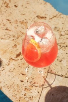 a drink sitting on top of a table next to a swimming pool in the sun