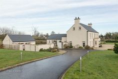 a large white house sitting on top of a lush green field next to a road