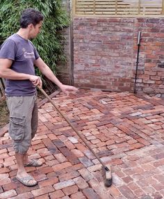 a man standing on top of a brick floor next to a fire hydrant with a broom in his hand