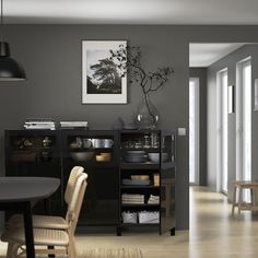 a dining room table and chairs in front of a gray wall