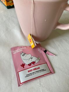 a pink mug with a tag on it sitting next to a packet of roost dreams