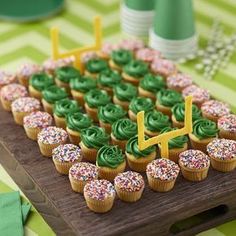 cupcakes with green frosting and sprinkles on a wooden board