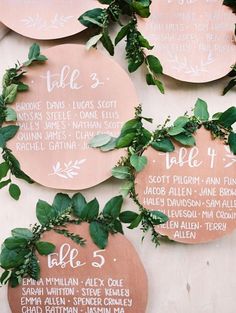 the wedding seating plan is displayed on a wall with greenery and wooden signs that read,