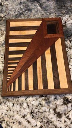 a wooden cutting board sitting on top of a granite counter next to a knife holder