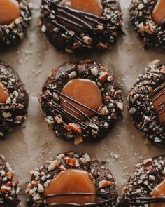 chocolate cookies covered in caramel drizzle and nuts on a sheet of wax paper