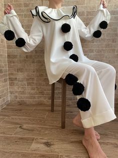 a woman sitting in a chair with black pom poms on her legs