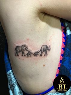 an elephant family tattoo on the back of a woman's left side ribcage