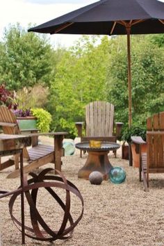 a patio with chairs and an umbrella in the middle, surrounded by graveled area