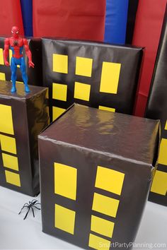 some black boxes with yellow squares on them and a spiderman figure in the middle