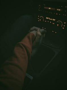 a person is driving in the dark with their hand on the steering wheel control button