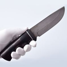 a person in white gloves holding a large knife