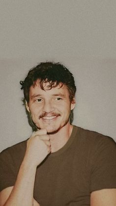 a man is smiling and posing for the camera with his hand on his chin while wearing a black t - shirt