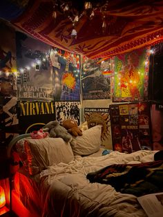 an unmade bed in a room with posters on the wall and lights hanging from the ceiling