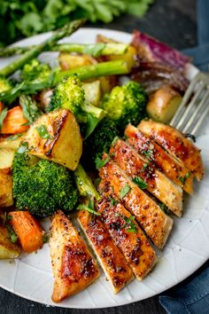 chicken, broccoli and potatoes on a white plate with a fork in it