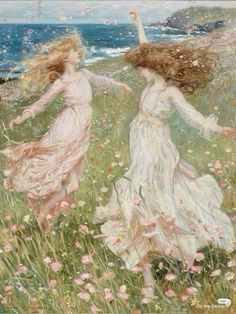 two women in white dresses are walking through the grass by the ocean with flowers on it