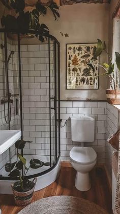 a white toilet sitting next to a shower in a bathroom under a painting on the wall