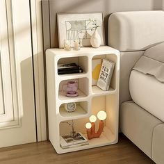 a white shelf sitting next to a bed on top of a hard wood floor covered in furniture