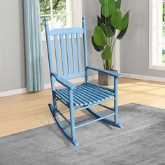 a blue rocking chair sitting on top of a rug next to a potted plant