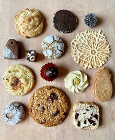 an assortment of cookies and pastries arranged on a piece of parchment paper with icing