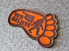 an orange and brown sticker with the words we believe on it's side