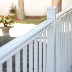 a close up of a white fence with flowers in the background