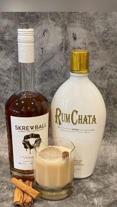 a bottle of rumchata next to some cinnamon sticks and a glass filled with liquid