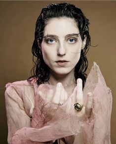 a woman with long hair and blue eyes is holding her hands up in front of her face