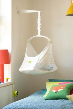 a white swing chair hanging from the ceiling in a child's bedroom with blue bedding