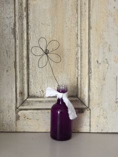 a purple bottle with a white ribbon tied to it sitting in front of a wooden door