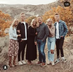 a group of people standing next to each other on a dirt road in the mountains