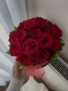 a person holding a large bouquet of red roses