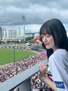 a woman standing in front of a baseball field