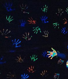 two children are playing with their hand prints on the dark ground in front of them