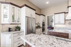 a large kitchen with white cabinets and marble counter tops, along with stainless steel appliances