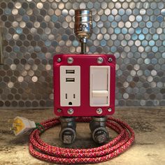 a red and white electrical outlet plugged in to a wall with silver circles behind it