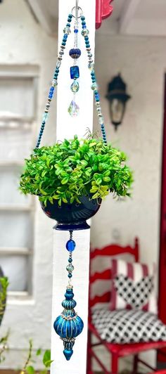 a potted plant hanging from a white pole with blue beads and glass ornaments on it