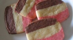 four pieces of pink and yellow cookies on a white plate